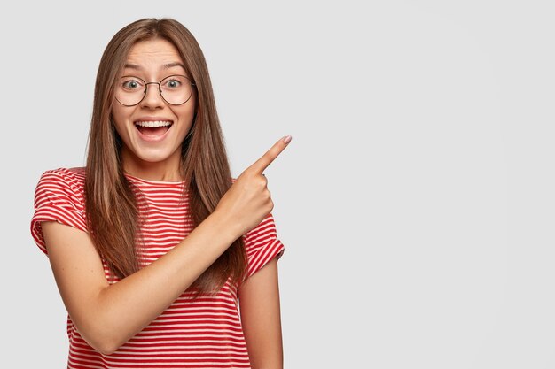 陽気な黒髪の女性の水平方向のショットは、カジュアルな服装で大喜びを感じます