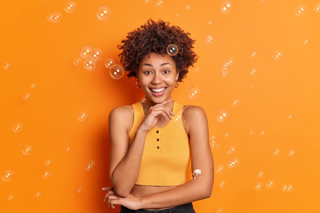 Free photo horizontal shot of cheerful dark skinned woman holds chin