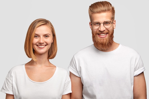 Horizontal shot of cheerful male and female dressed in casual white t shirts