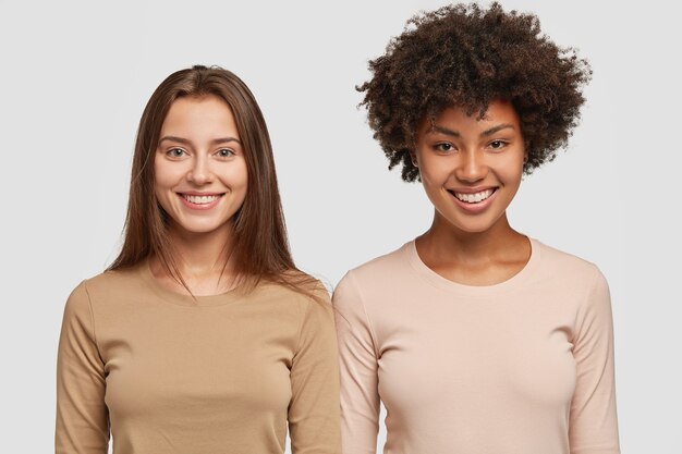 Horizontal shot of cheerful multiethnic women have appealing appearance and satisfied expressions