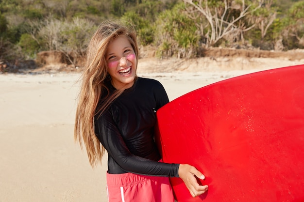 Free photo horizontal shot of cheerful professional surfer feels andrenaline after competitions and breaking waves on ocean