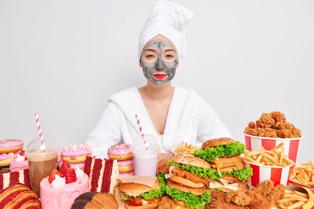 Horizontal shot of confident Asian woman surrounded by junk food