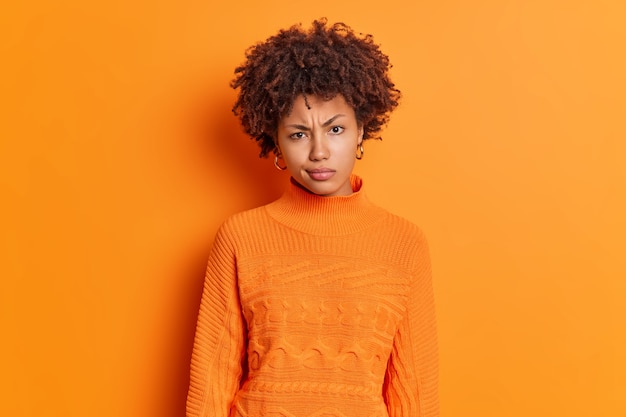 Horizontal shot of displeased young African American woman frowns face looks angrily at camera