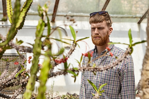 Free photo horizontal shot of handsome serious young male with thick beard wearing checkered shirt