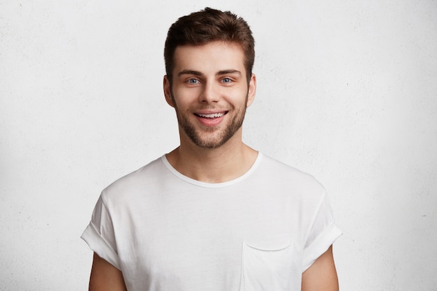 Free photo horizontal shot of handsome young guy with blue eyes and bristle, has positive expression