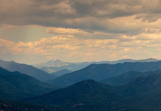 Horizontal shot of hills in different shades of blue and the cloudy evening sky