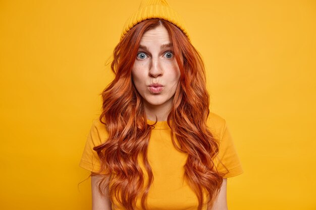 Horizontal shot of impressed redhead woman looks with great wonder, keeps lips folded