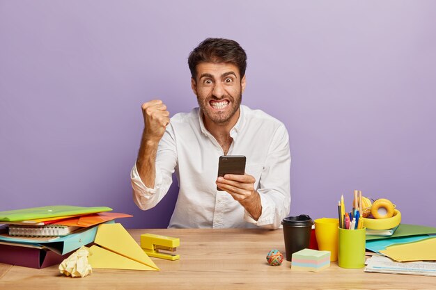 Horizontal shot of irritated employee sitting at the office desk