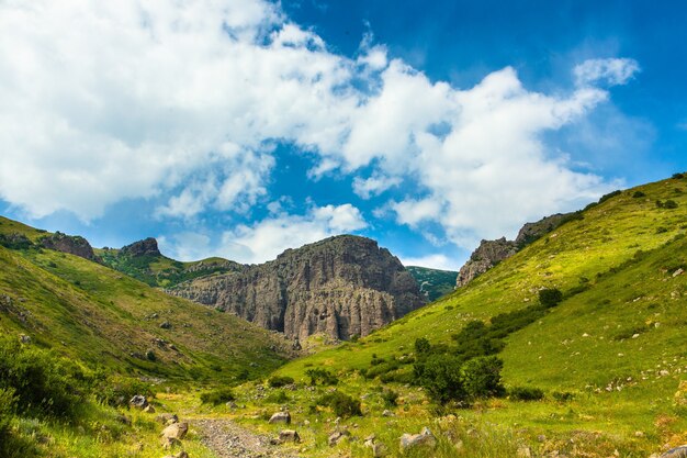 Horizontal shot of mountains covered in green under the beautiful cloudy sky