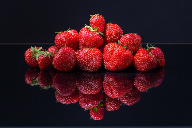 Horizontal shot of a pile of red Croatian strawberries on a black reflecting surface