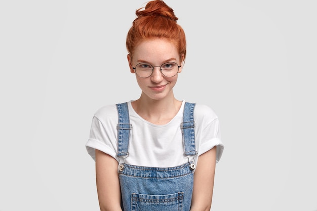 Free photo horizontal shot of pleasant looking ginger young european woman in round transparent glasses