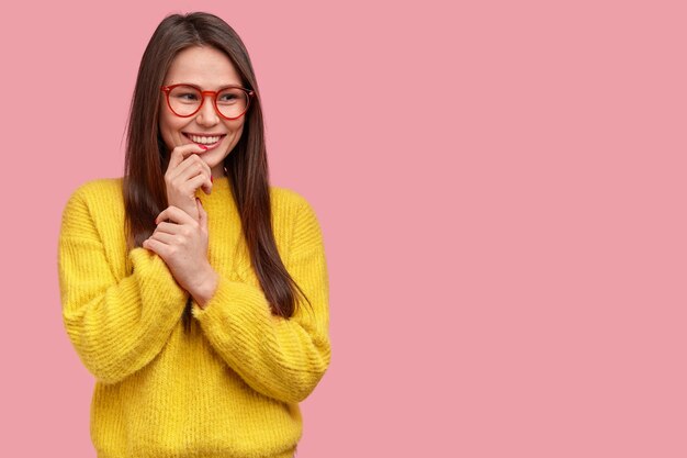 Horizontal shot of pleasant looking woman with satisfied expression, has intention to develop something