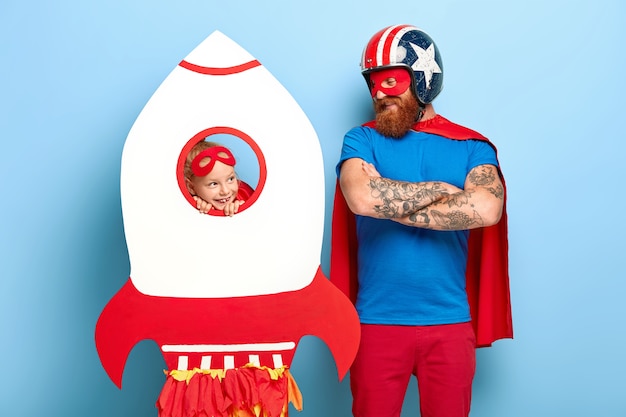 Horizontal shot of satisfied man wears headgear and red cape