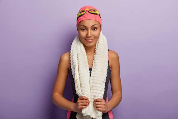 Free photo horizontal shot of satisfied professional female swimmer has white towel on neck, attends sport section