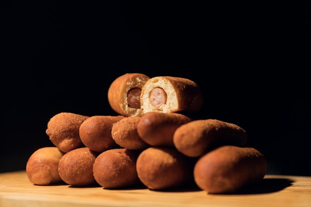 Horizontal shot of several corn dogs with one cut up on a wooden surface