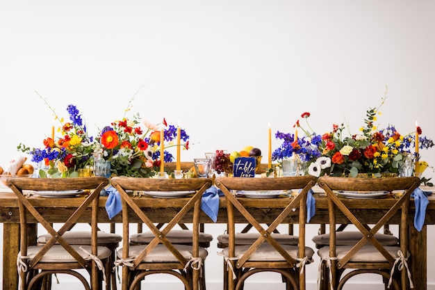 Free photo horizontal shot of a table with wooden chairs decorated with colorful flowers and candles