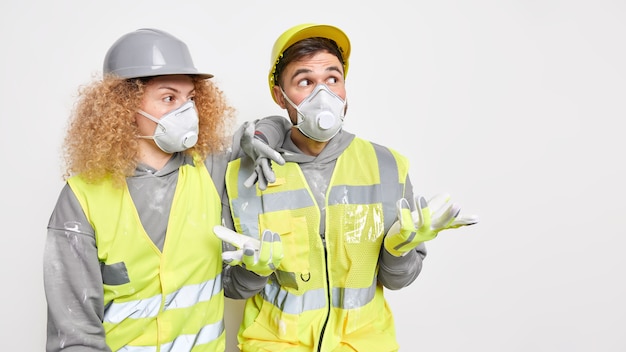 Free photo horizontal shot of of two construction workers wear helmet protective masks and uniform