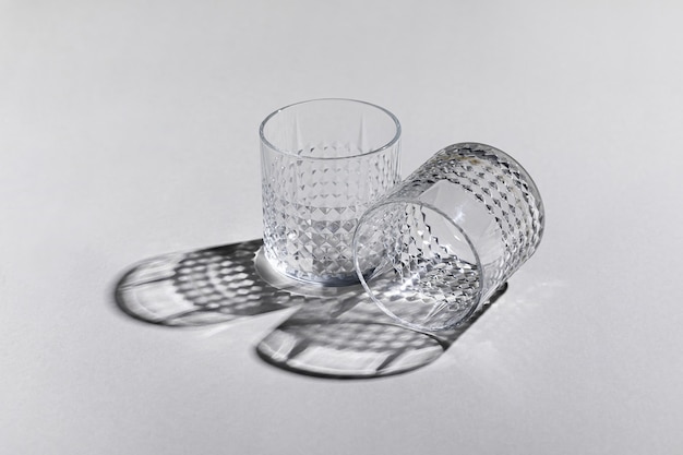 Free photo horizontal shot of two empty old-fashioned glasses on the white surface with shadows