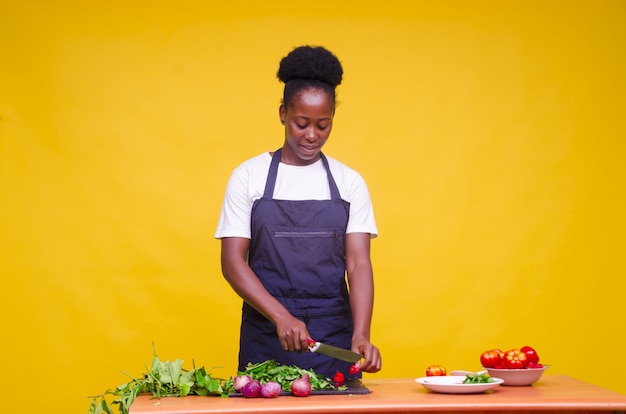 Free photo horizontal shot of a young attractive african cook cutting vegetables with a knife