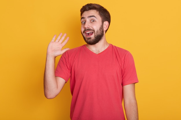 Горизонтальный снимок возбужденного молодого человека в красной повседневной футболке