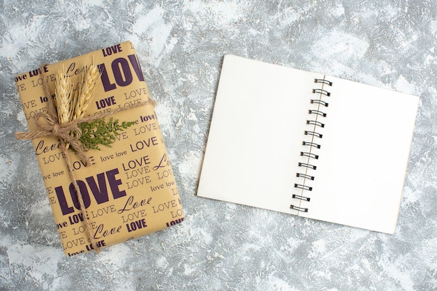 Horizontal view of beautiful big packed gift and open notebook on ice surface