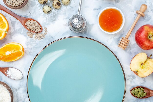 Horizontal view of blue empty plate and ingredients for the healthy food set on ice background