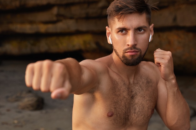 Horizontal view of concentrated powerful male boxer practices different tricks