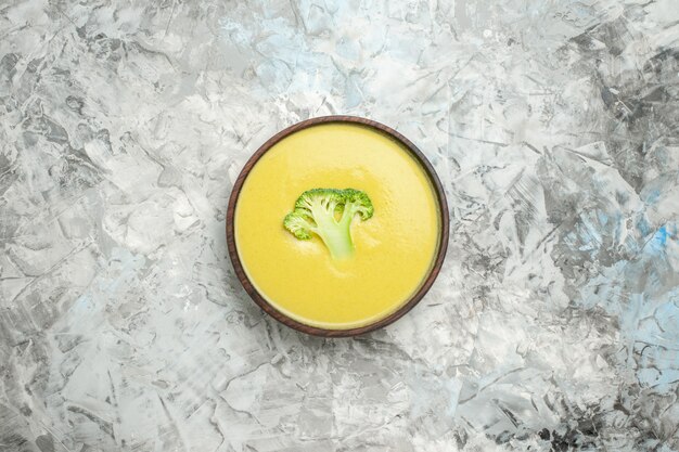 Foto gratuita vista orizzontale della crema di zuppa di broccoli in una ciotola marrone sul tavolo bianco
