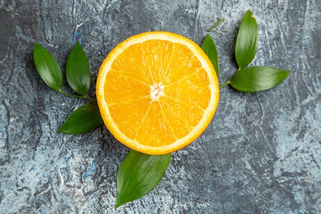 Horizontal view of cut in half fresh orange with leaves on gray background stock photo