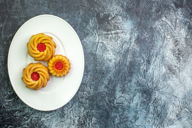 Horizontal view of delicious biscuits on a white plate on the right side on dark surface