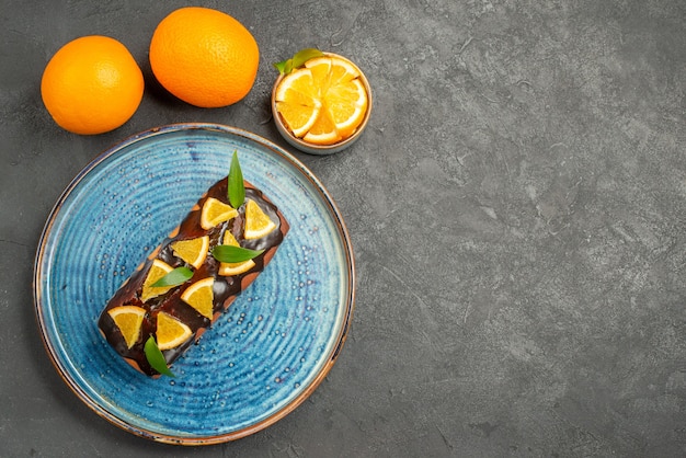 Free photo horizontal view of delicious cake and orange on black table