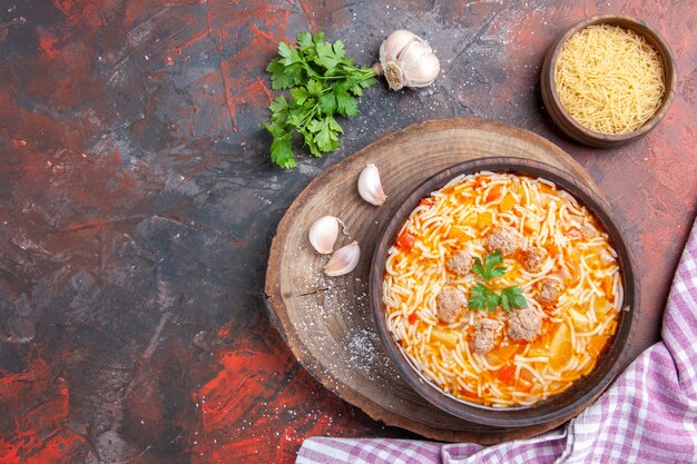 Horizontal view of delicious noodle soup with chicken on wooden cutting board greens spoon garlic on dark background