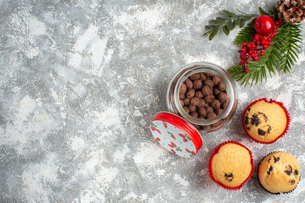 얼음 표면의 왼쪽에 유리 냄비와 전나무 가지에 맛있는 작은 컵 케이크와 초콜릿의 가로보기