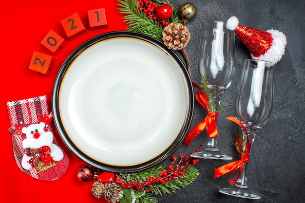 Horizontal view of dinner plates decoration accessories fir branches xsmas sock glass goblets on dark table