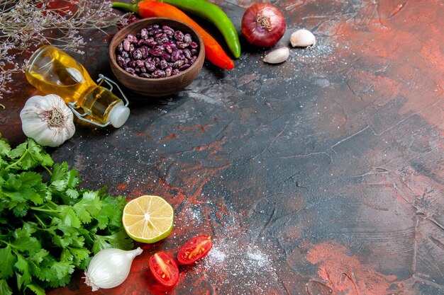 Horizontal view of dinner preparation with foods and beans oil bottle and a bunch of green lemon tomato on mixed color table