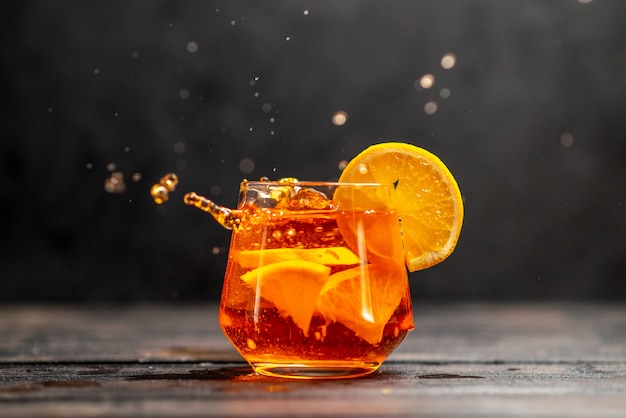 暗いテーブルの上のオレンジ色のライムとガラスの新鮮なおいしいジュースの水平方向のビュー