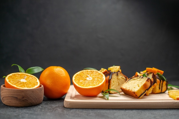 Free photo horizontal view of fresh lemon slices and freshly baked chopped cake slices on dark table