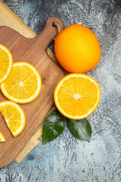 Horizontal view of fresh lemon slices on wooden cutting board on newspaper on gray background stock photo