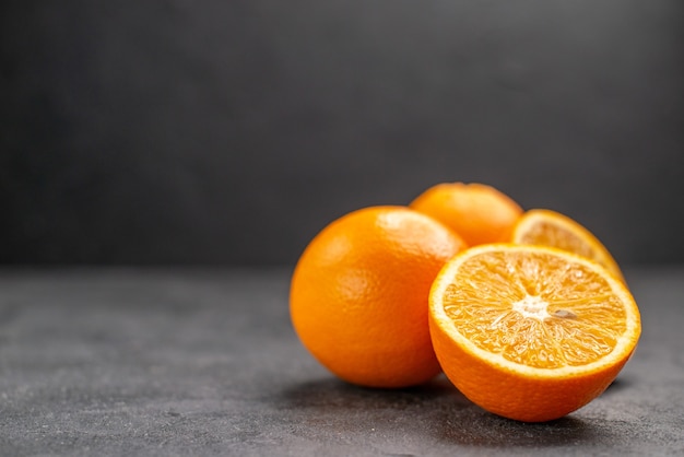 Horizontal view of fresh whole and sliced lemons on dark table 