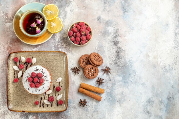 Horizontal view of freshly baked cake with raspberries a cup of black tea with lemon cinnamon lime