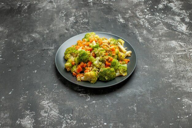 Horizontal view of healthy meal with brocoli and carrots on a black plate on gray table