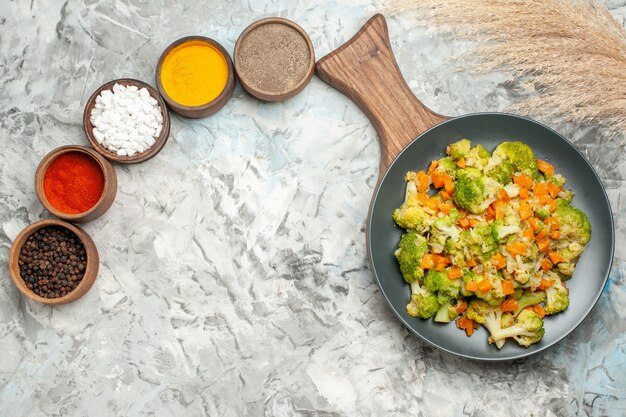 horizontal view of healthy vegetable salad different spices on white table