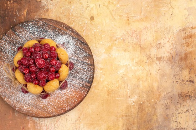 Horizontal view of homemade soft cake with fruits on wooden cutting board on mixed color table