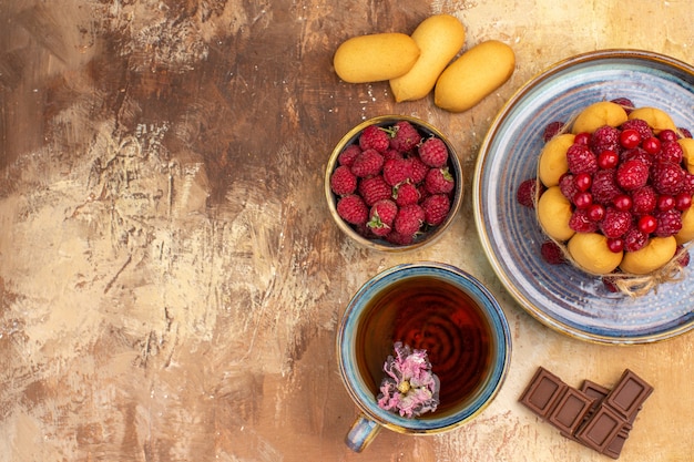 Horizontal view of hot herbal tea soft cake with fruits chocolate bars on mixed color table