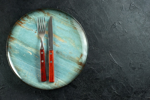 Free photo horizontal view of meal cutlery on a blue plate on the right side on dark surface