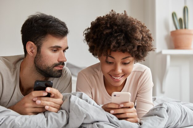 Horizontal view of mixed race girlfriend and boyfriend, blogg in social networks on mobile phones