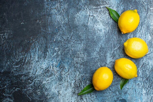 Horizontal view of organic natural fresh lemons with leaves on the right side on dark background