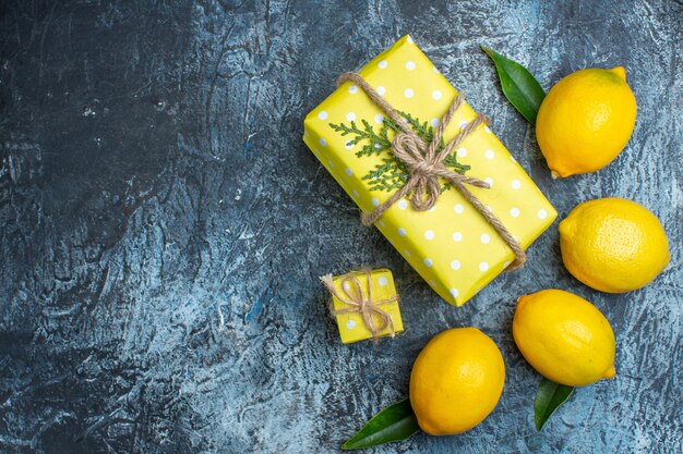 Horizontal view of organic natural fresh lemons with leaves and yellow gift boxes on dark background