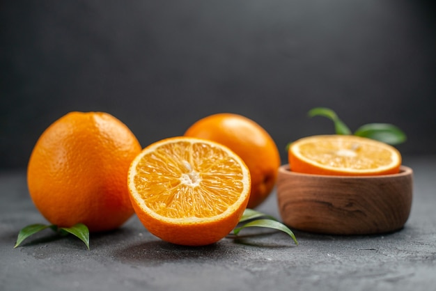 Horizontal view of set of whole and cut in half fresh oranges on dark table