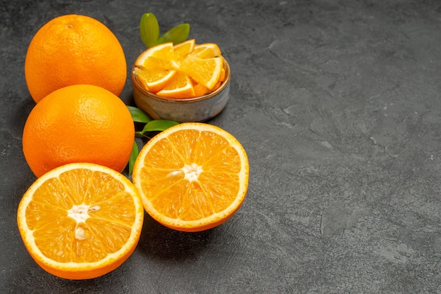 Horizontal view of set of yellow whole and chopped oranges on dark table